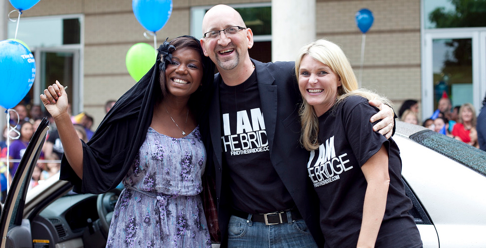 Three church members embracing each other's shoulders and smiling for the camera.